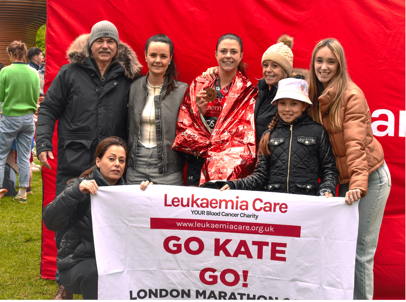 The image shows Leukaemia Care supporters holding a custom sign at London Marathon that says Go Kate.