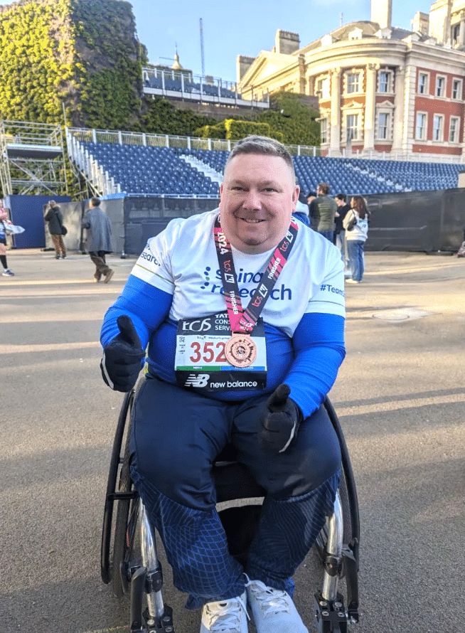 Foto de um arrecadador de fundos da Spinal Research em uma cadeira de rodas durante a Maratona de Londres.