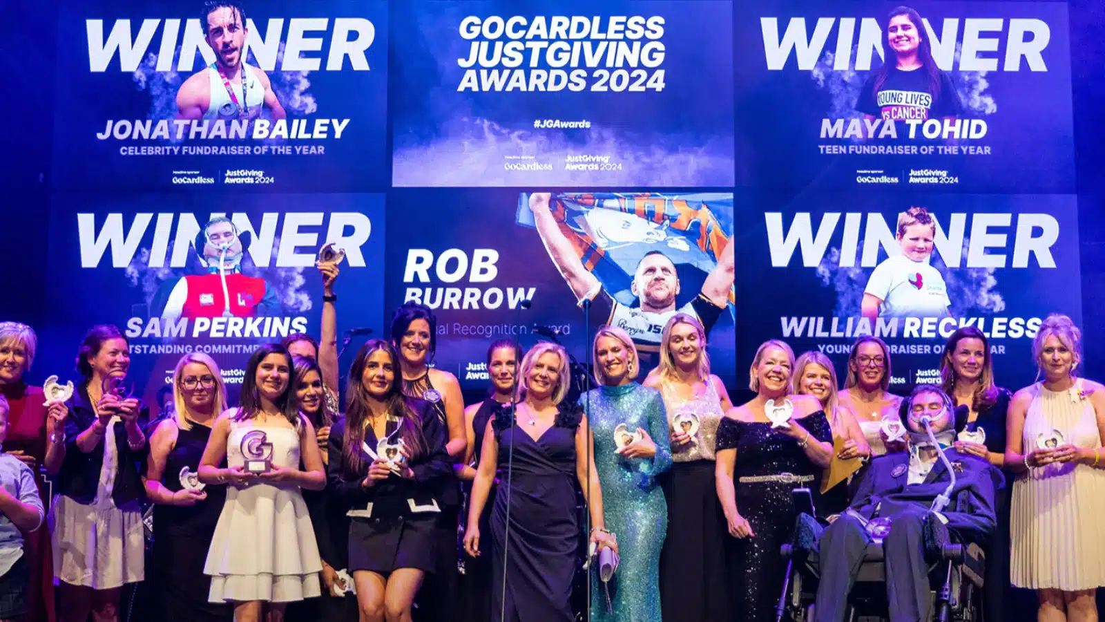 Photo showing the 2024 GoCardless JustGiving Awards winners holding their trophies on stage.