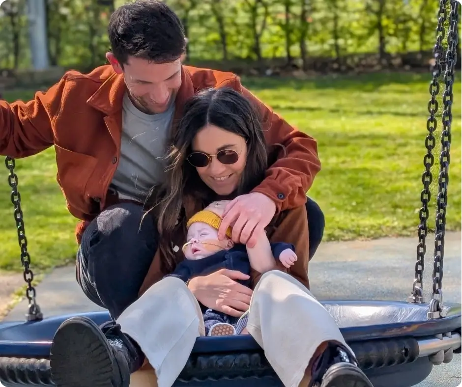 Image showing Alex and Selina smiling with their son Otis on a swing.