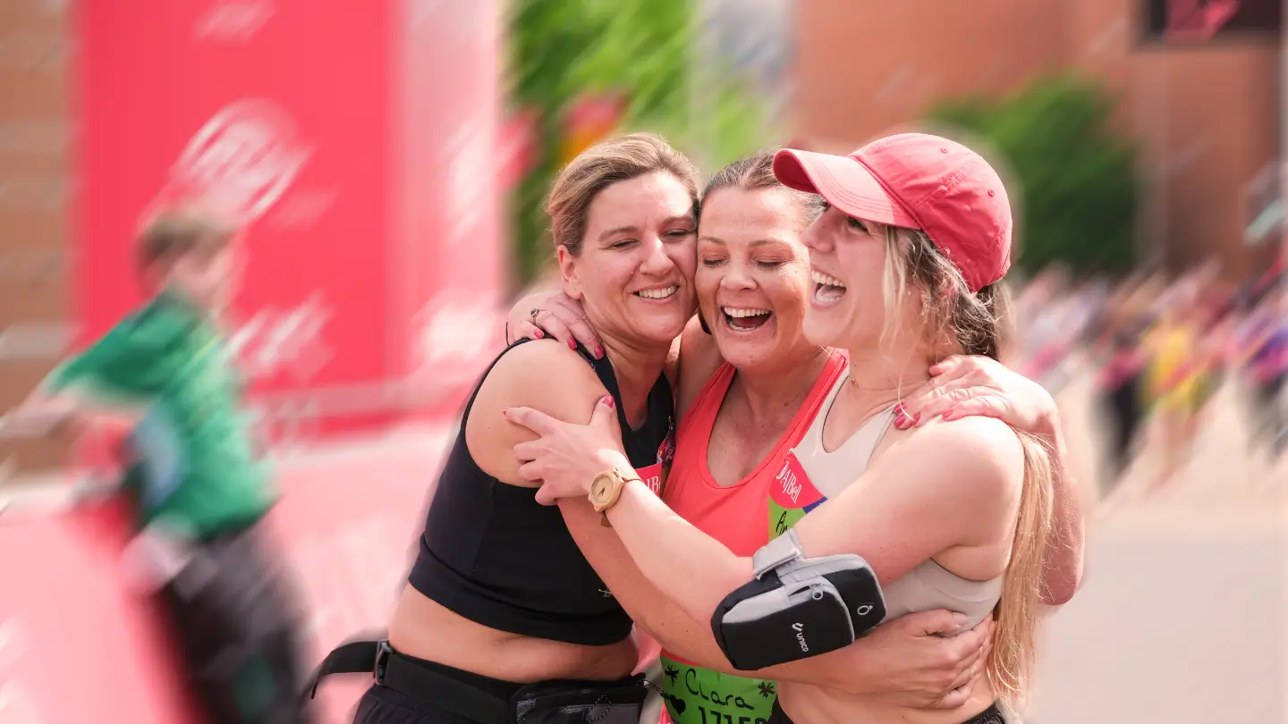Three event participants smiling and hugging in celebration